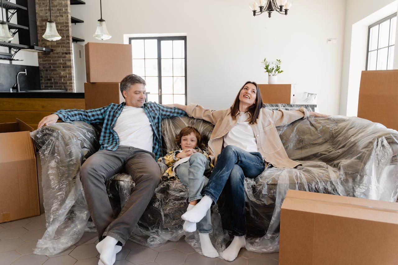 Smiling family sitting on a covered sofa in their new home with moving boxes.