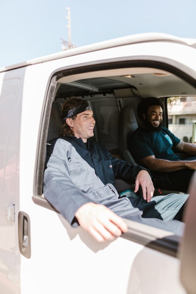 Two movers enjoy driving a moving van, embodying teamwork and friendship.
